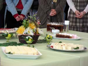 緑のクロスをひいたテーブルには花が飾られ、ケーキとサンドイッチ、飲み物が準備されています。